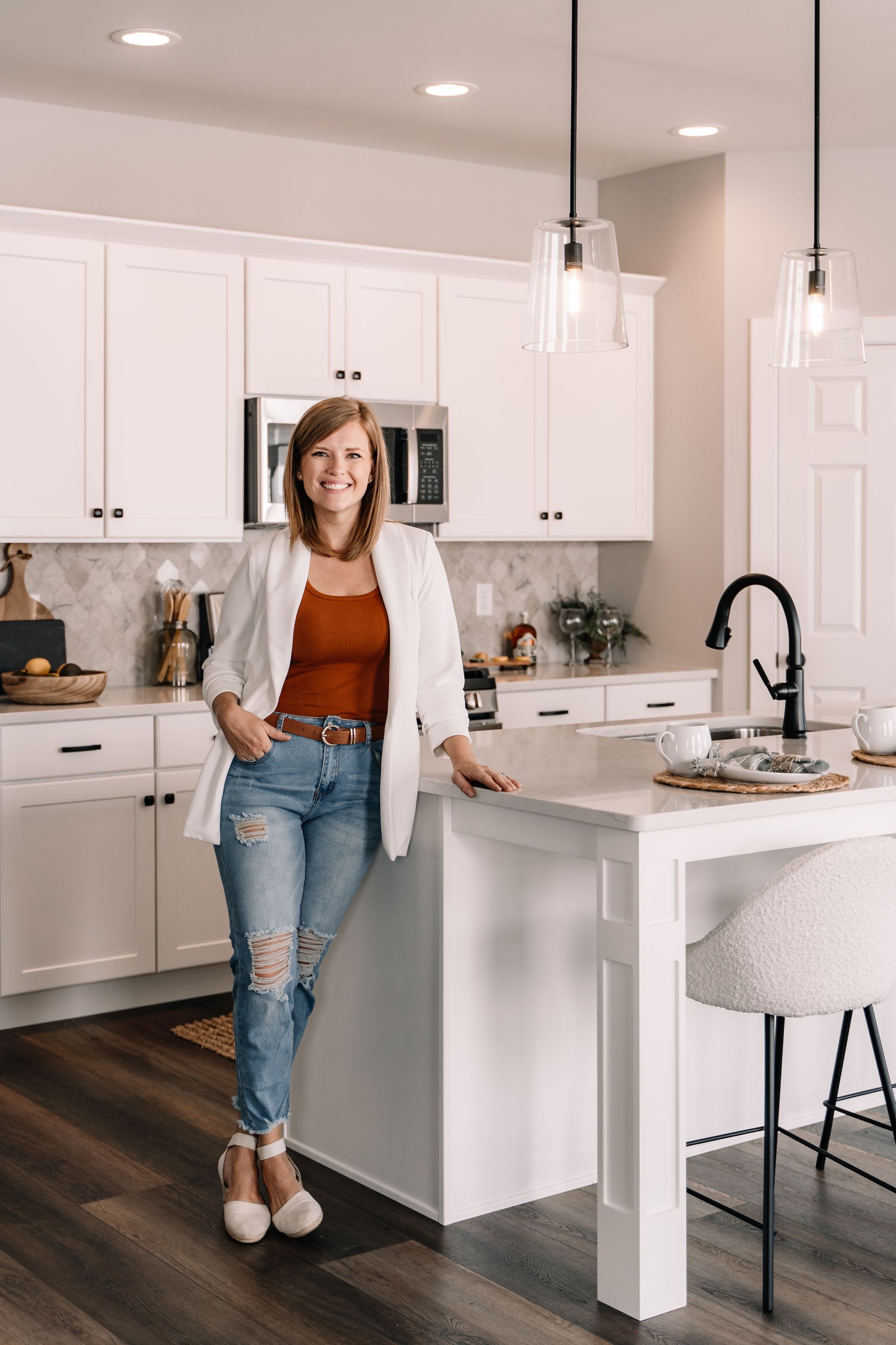 A woman is standing in a kitchen leaning on a counter.