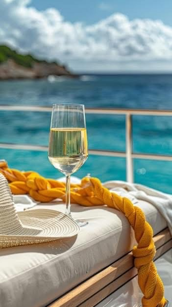 Glass of white wine on a boat, straw hat, yellow rope, ocean view.