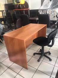 Un escritorio y una silla de madera están colocados sobre un suelo de baldosas.