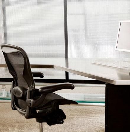 Una silla se encuentra frente a un escritorio con una computadora sobre ella.