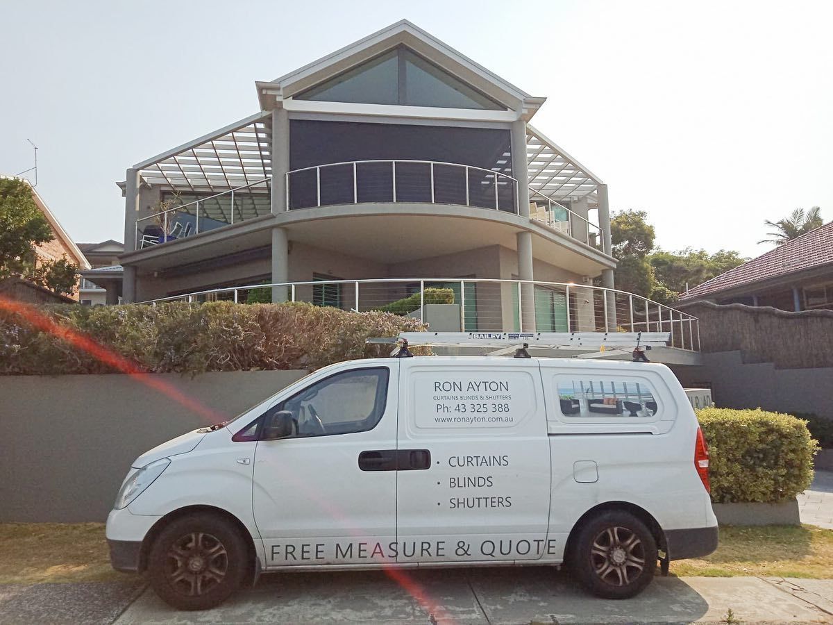 A white van is parked in front of a large house. — Ron Ayton Curtains, Blinds & Shutters In Shelly Beach, NSW