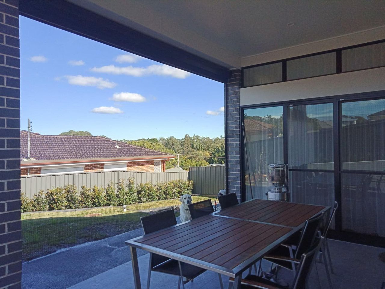 A Patio With A Table And Chairs And A View Of A House — Ron Ayton Curtains, Blinds & Shutters In Cooranbong, NSW