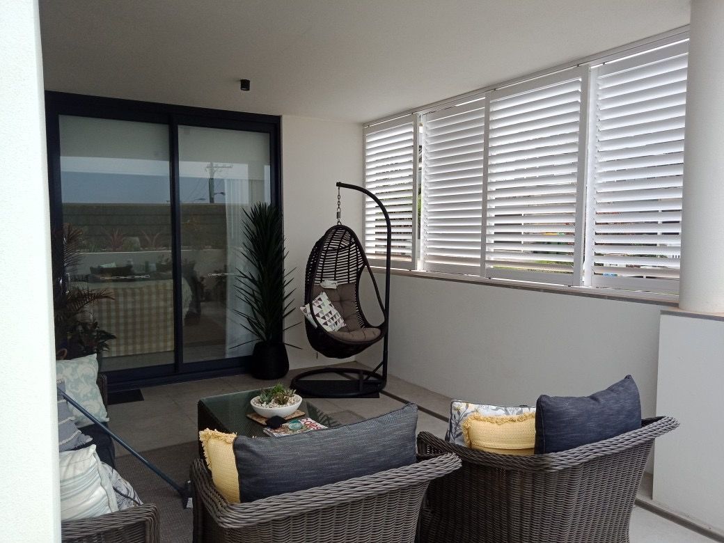 A Balcony With Wicker Furniture And A Hanging Chair — Ron Ayton Curtains, Blinds & Shutters In Shelly Beach, NSW