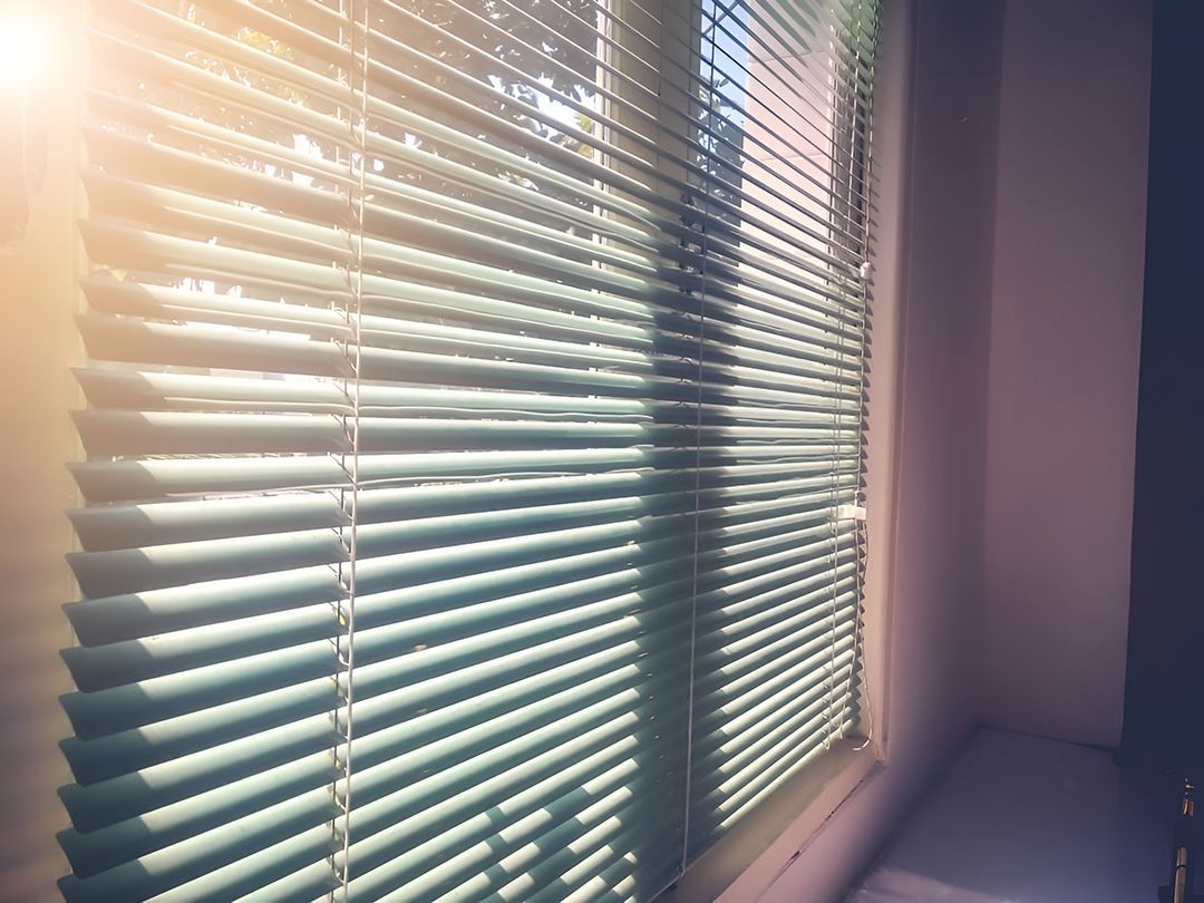 The Sun Is Shining Through The Blinds Of A Window — Ron Ayton Curtains, Blinds & Shutters In Shelly Beach, NSW