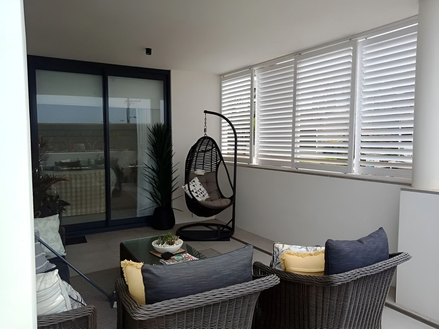Patio with Wicker Furniture and Shuttered Windows — Ron Ayton Curtains, Blinds & Shutters In Shelly Beach, NSW