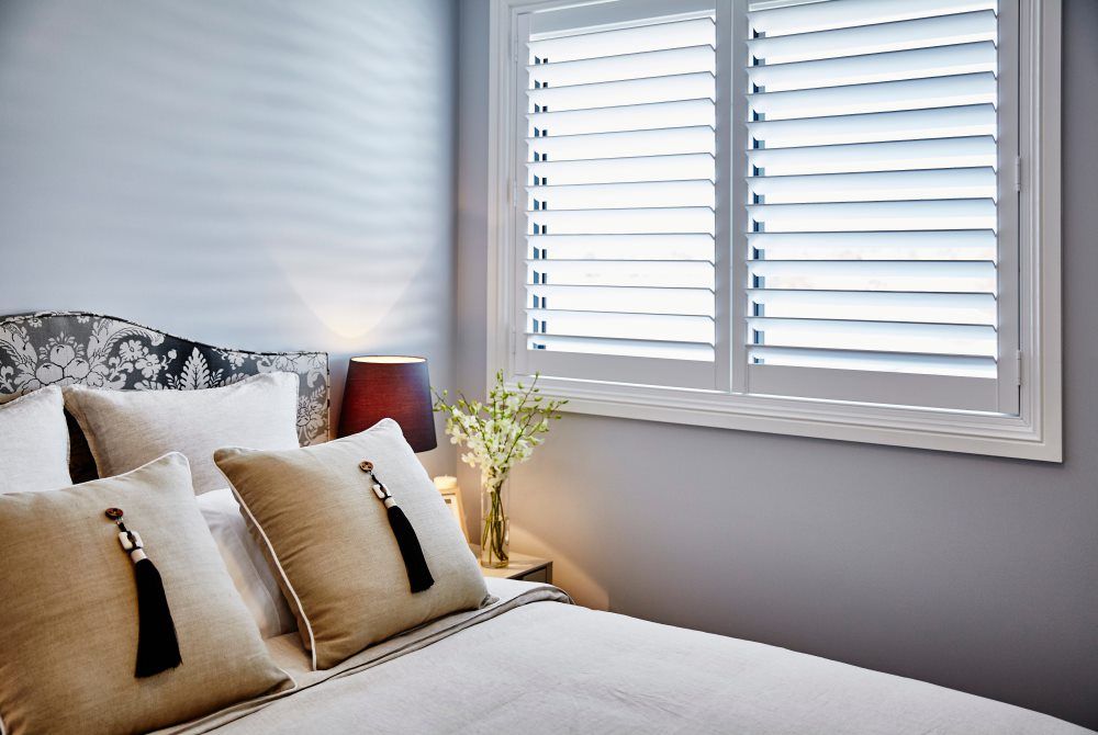 A Bed And A Window With Shutters — Ron Ayton Curtains, Blinds & Shutters In Shelly Beach, NSW