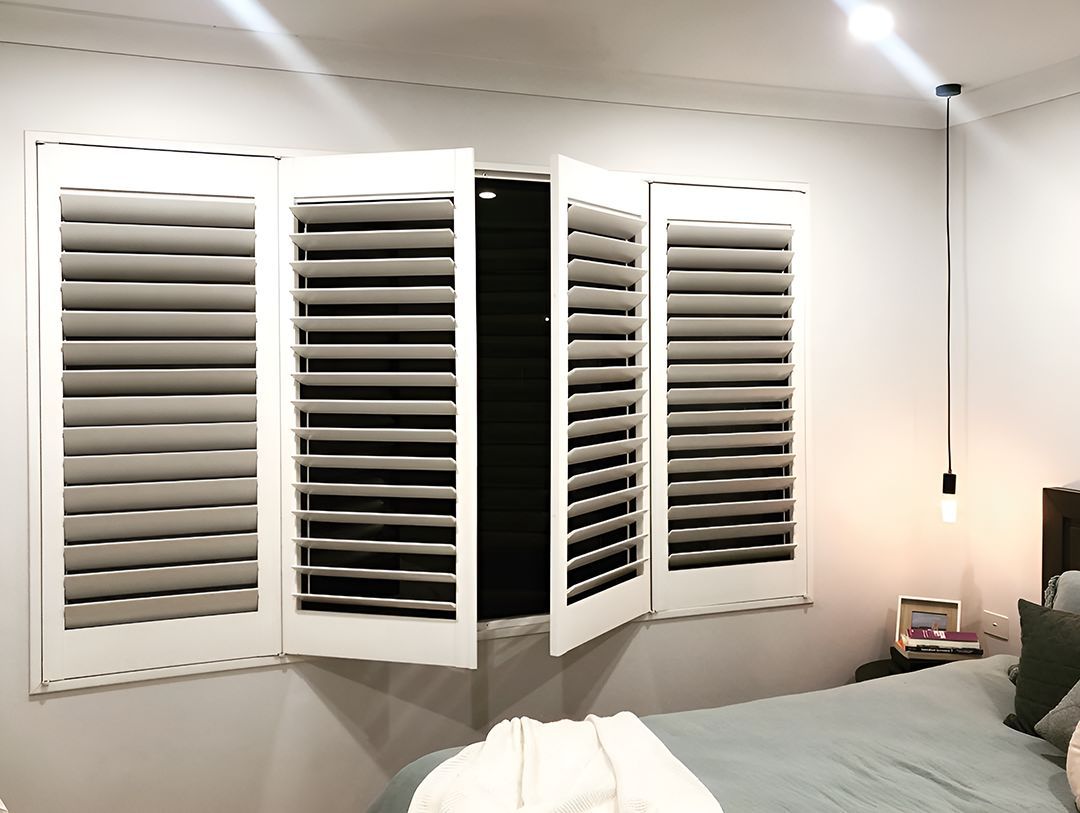 A Bedroom With A Bed And Shutters On The Windows — Ron Ayton Curtains, Blinds & Shutters In Shelly Beach, NSW