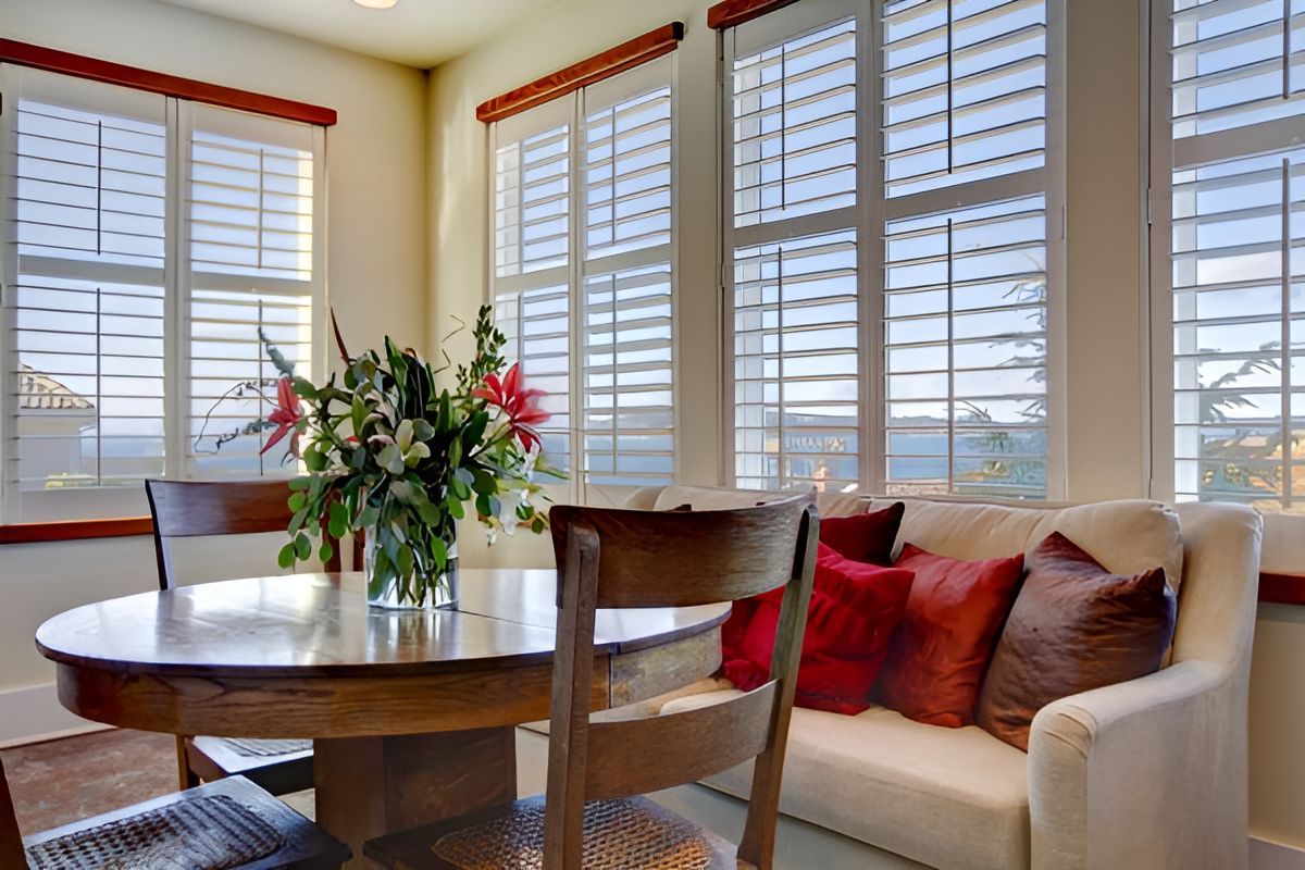 A Living Room With A Vase Of Flowers On The Table — Ron Ayton Curtains, Blinds & Shutters In Morisset, NSW