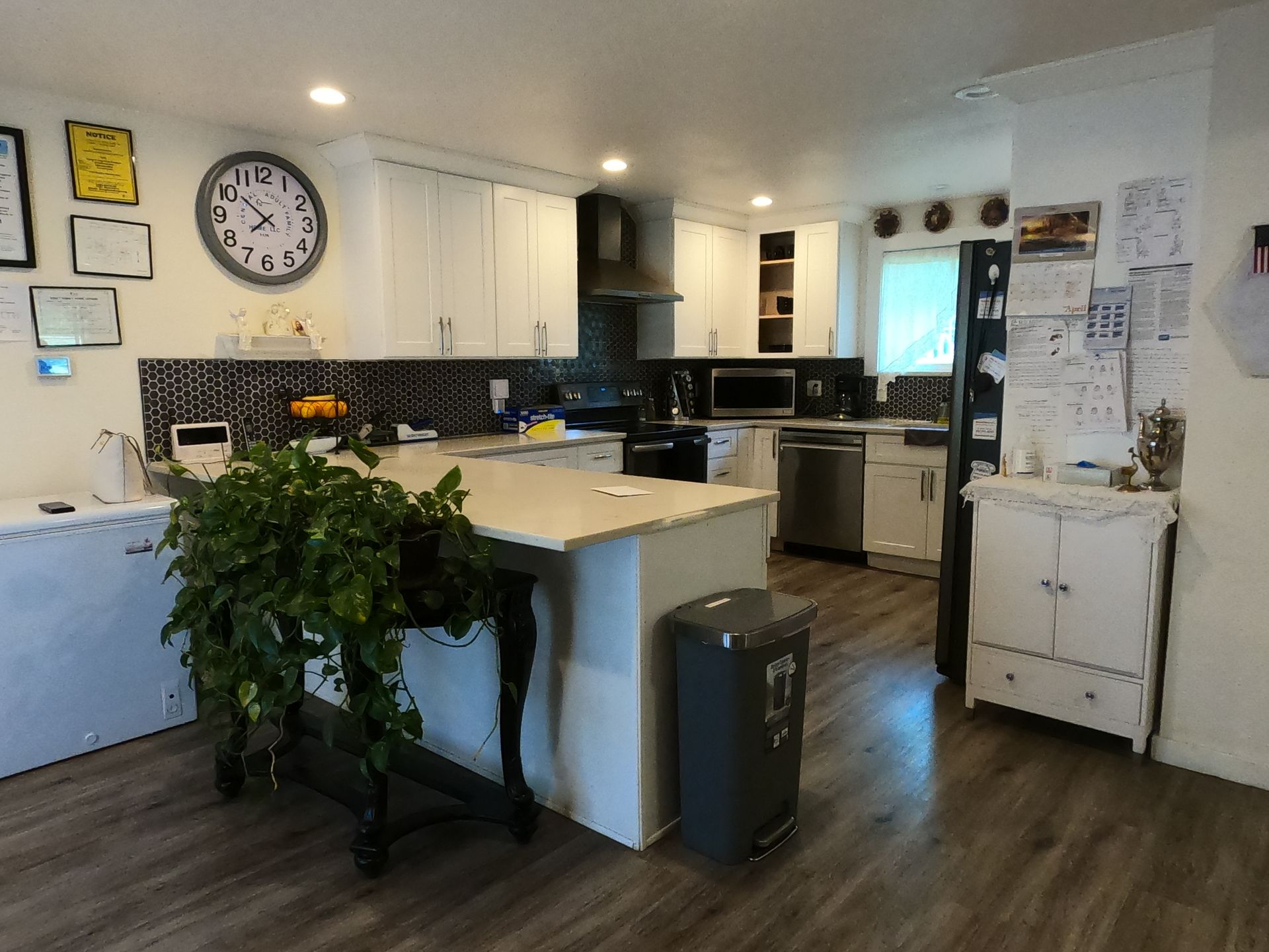 Kitchen with white cabinets, island, stainless steel appliances, and a large clock.