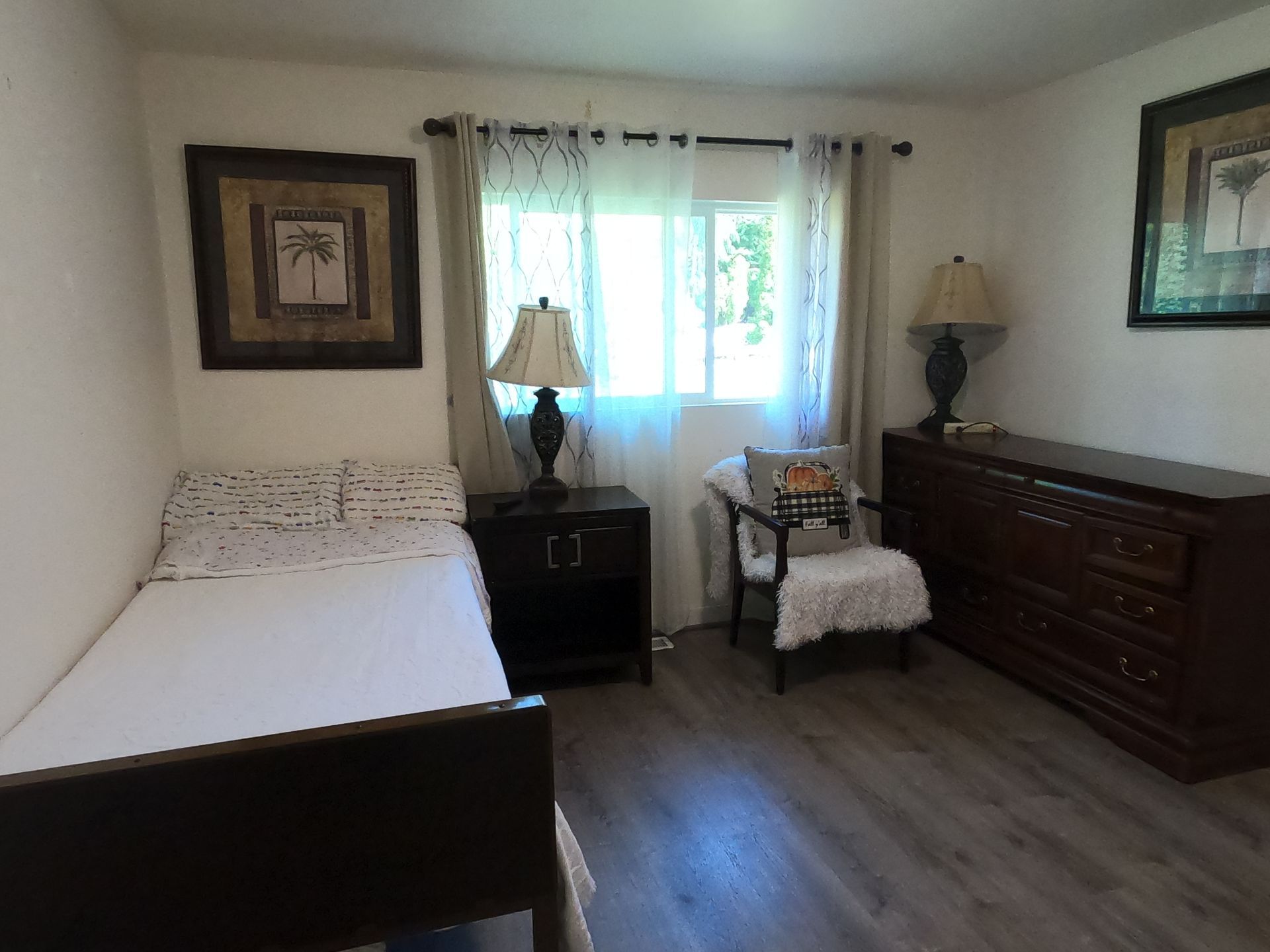 Bedroom with a bed, dresser, chair, and a nightstand with a lamp.