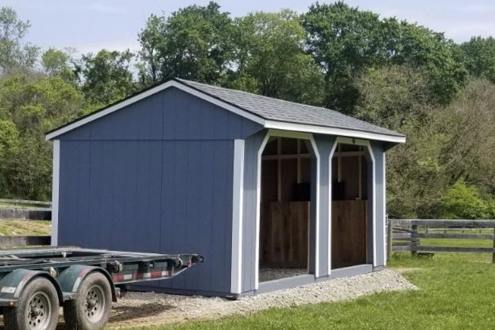 A blue shed with a trailer attached to it.