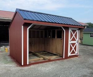 A red barn with a black roof and white trim is being built.