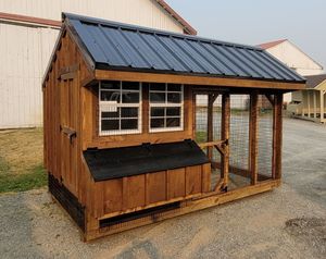 A small wooden chicken coop with a metal roof