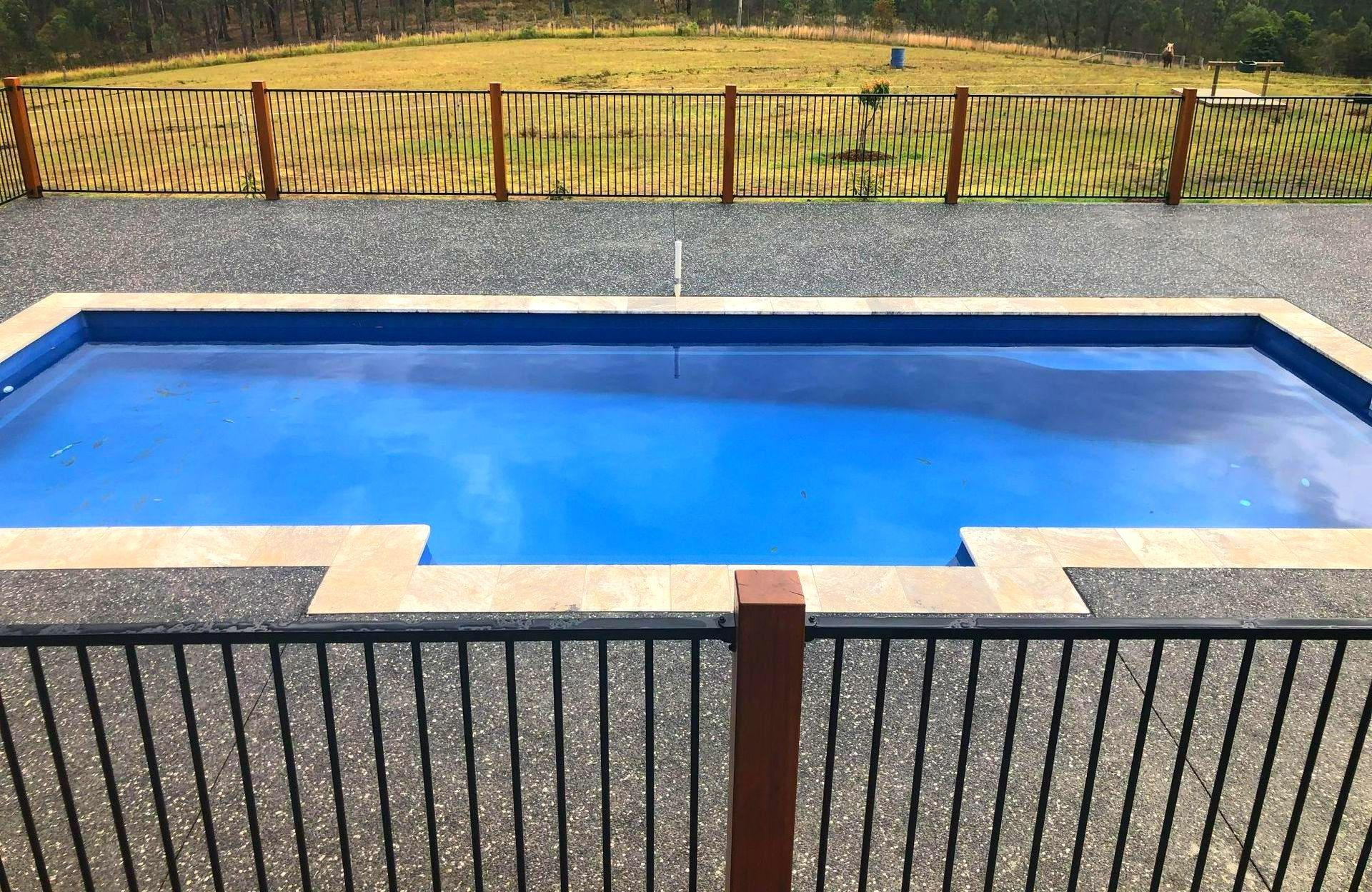 A large swimming pool with a fence around it — Steve Merrick Family Swimming Pools in Diamond Beach, NSW