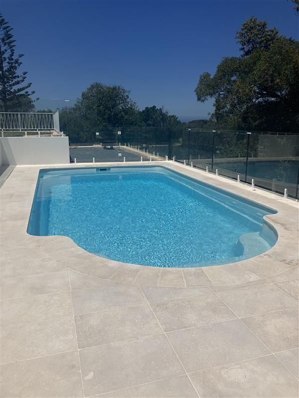 A large swimming pool with a glass fence around it — Steve Merrick Family Swimming Pools in Failford, NSW