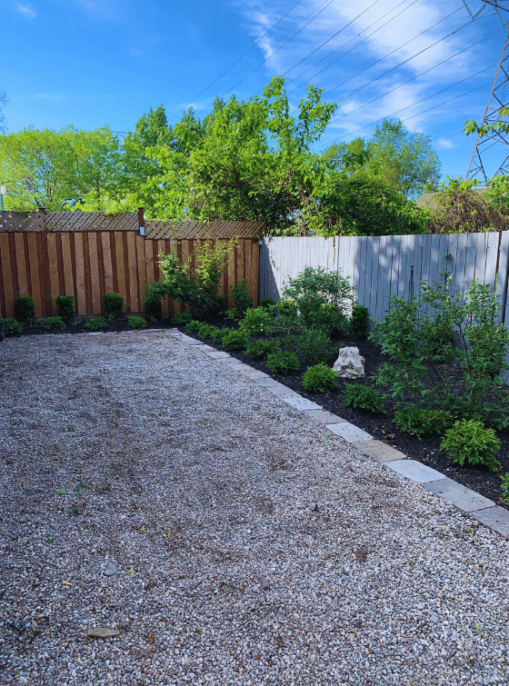 A gravel driveway with a wooden fence in the background.
