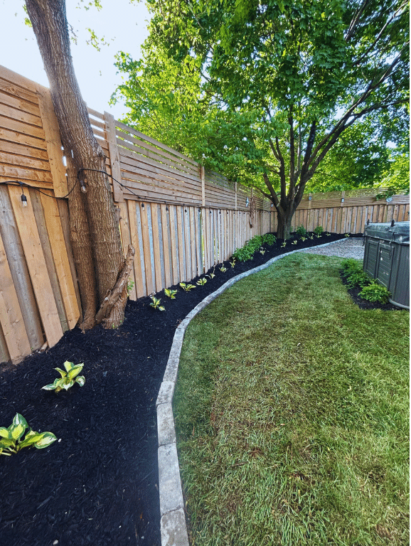 A wooden fence surrounds a lush green lawn.