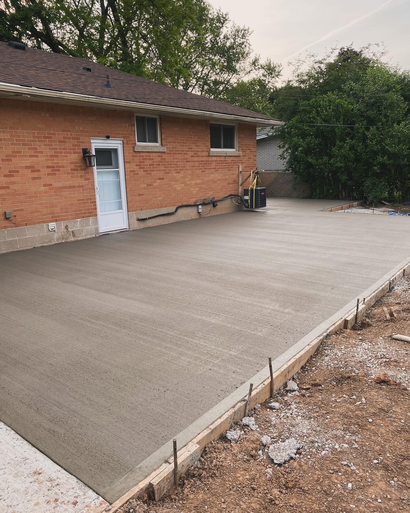 Wooden double gate with a brown frame in a paved area next to a brick building.