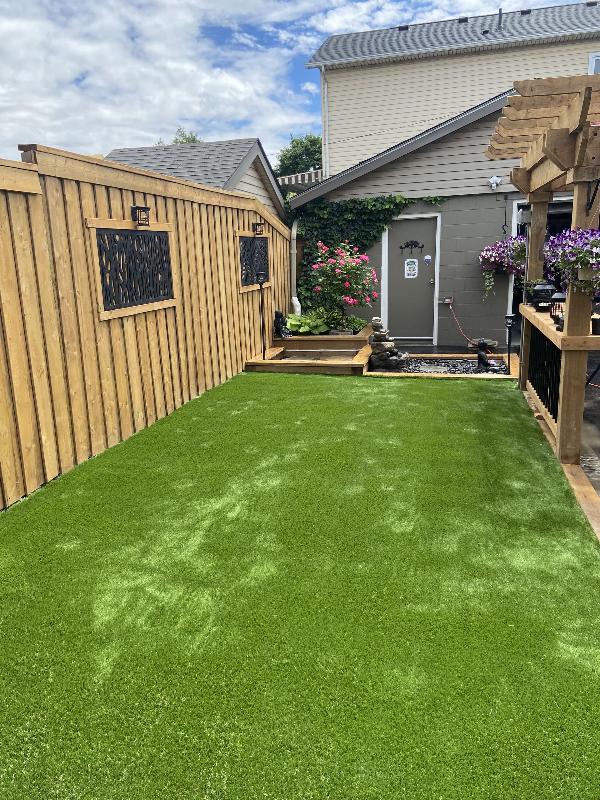 A backyard with a wooden fence and a lush green lawn.