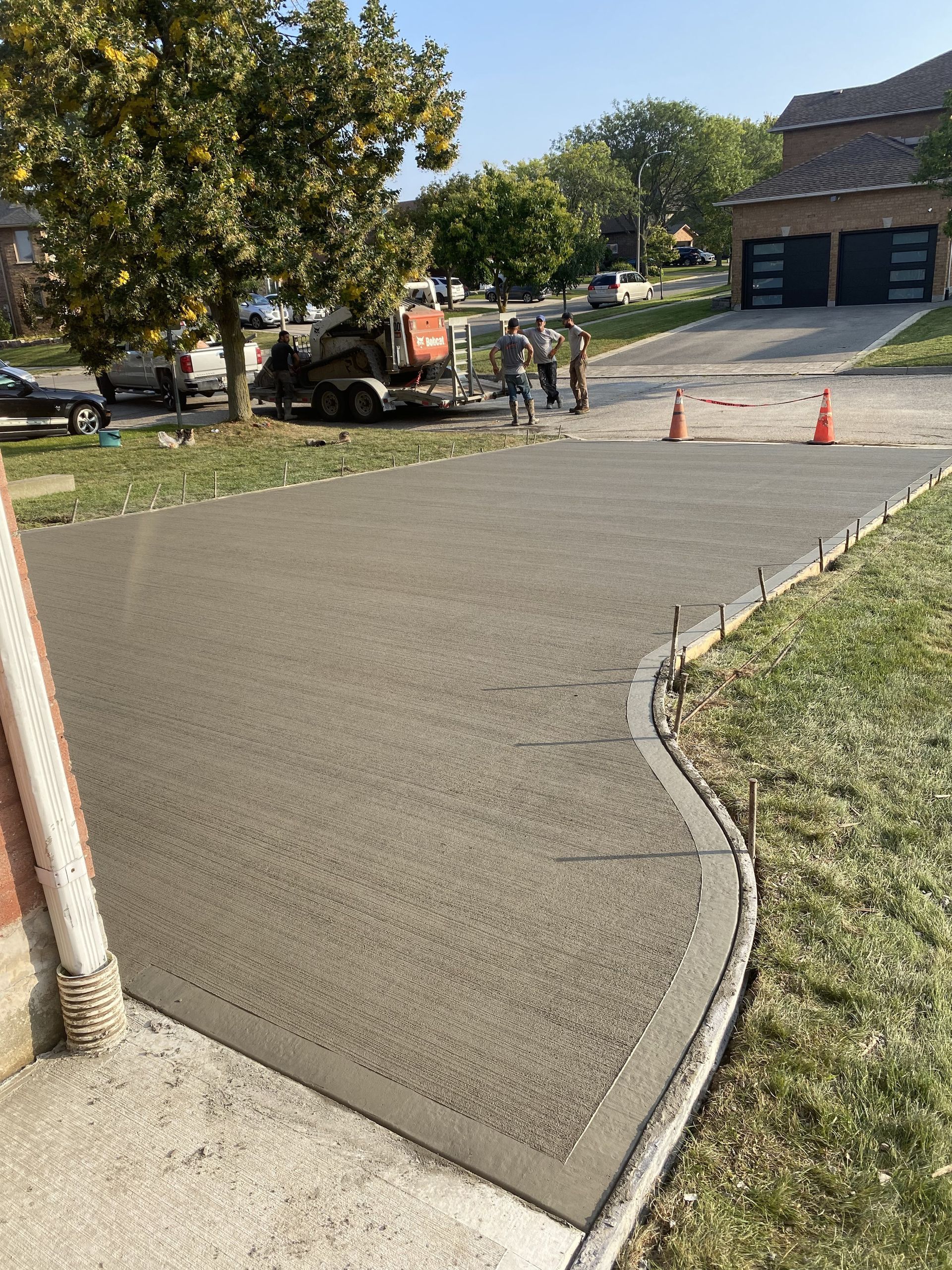 Wooden fence along the side of a brick house with a small grassy lawn.