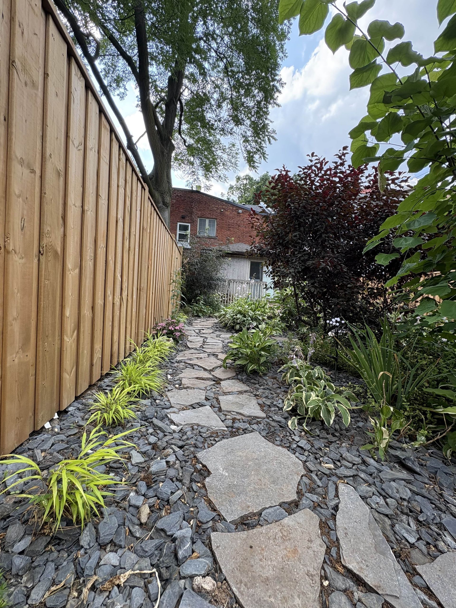 A stone path leading to a wooden fence in a garden.