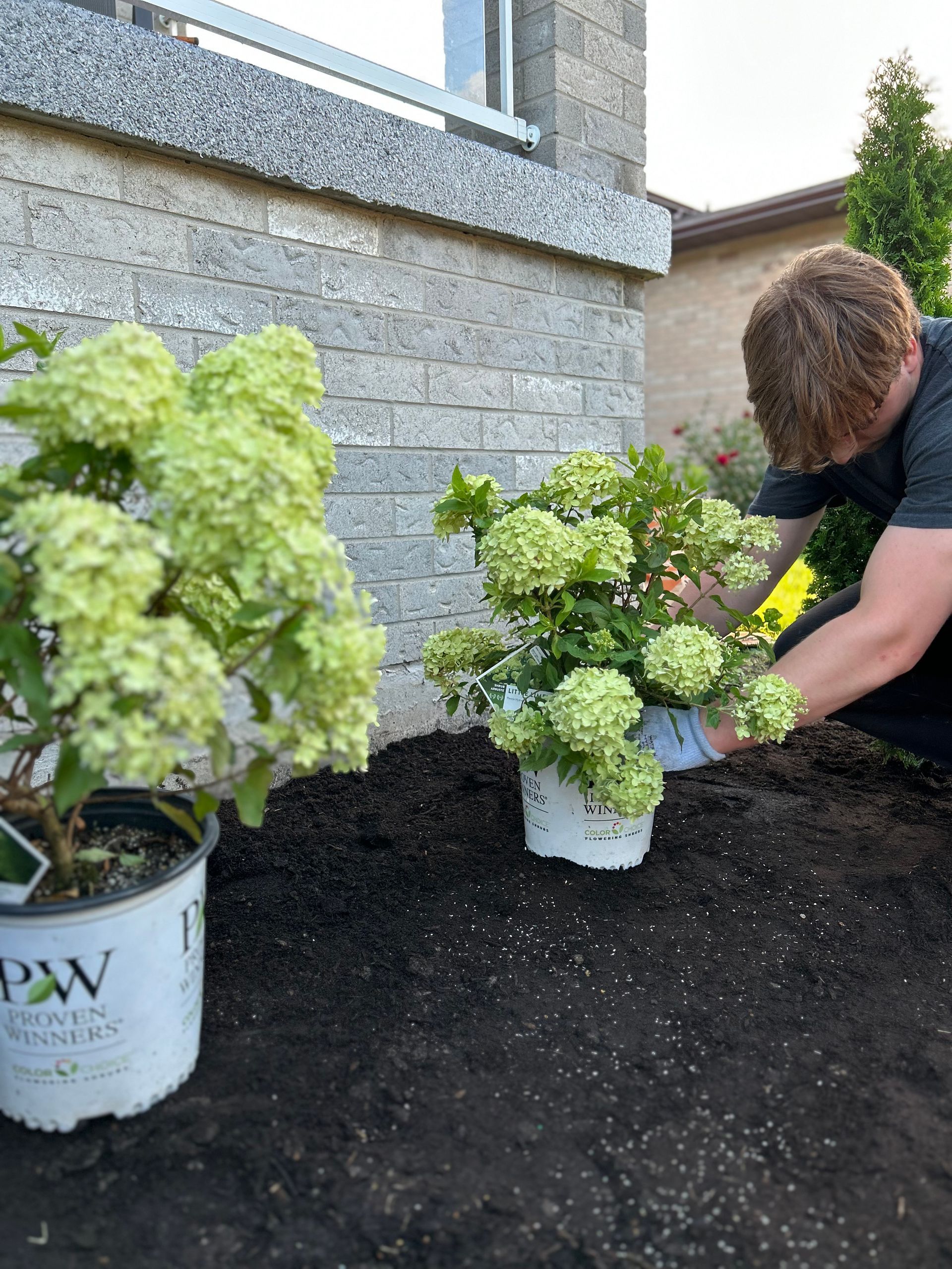A man is planting flowers in pots in a garden.
