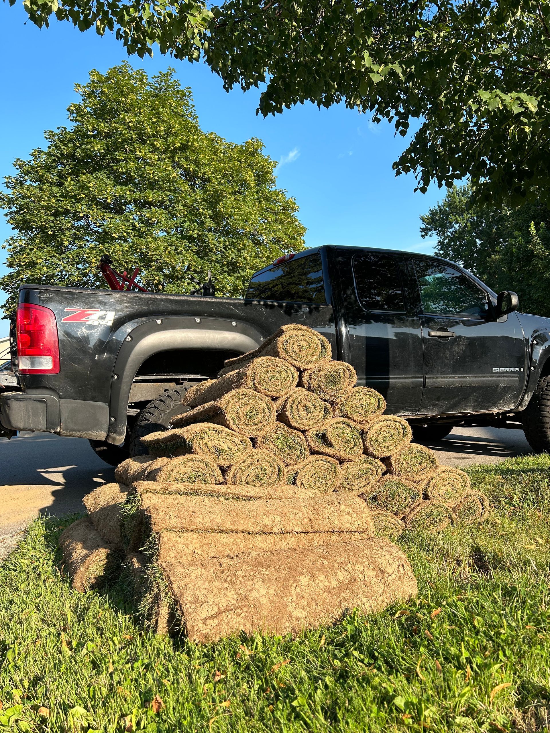A black truck is parked next to a pile of grass