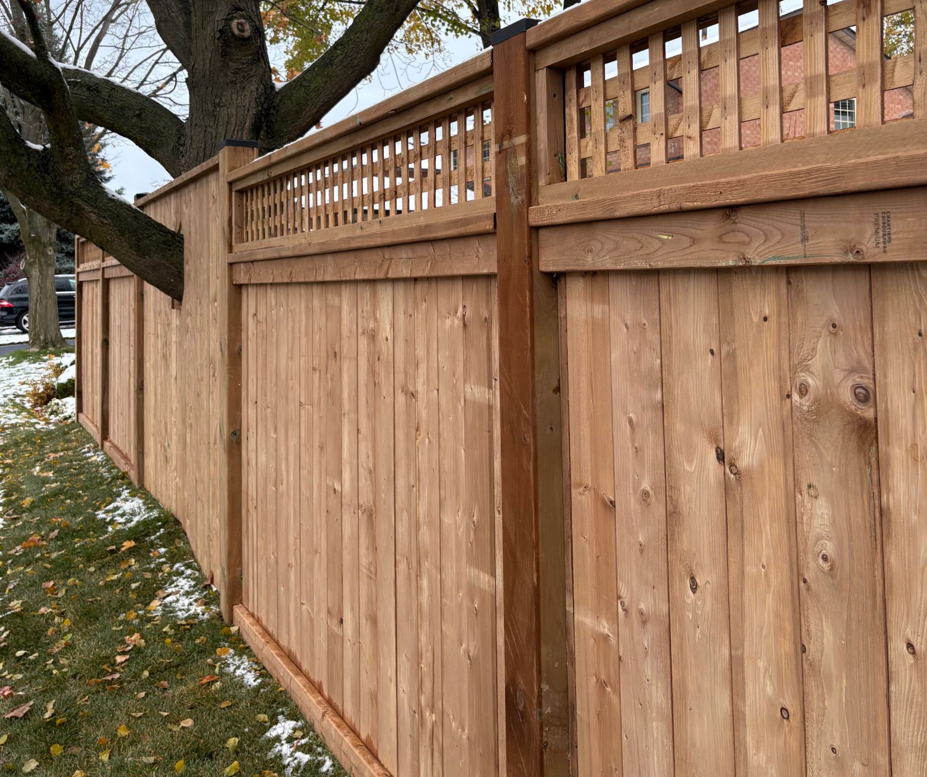Concrete driveway leading to a brick house with a garage; green grass and fallen leaves on either side.