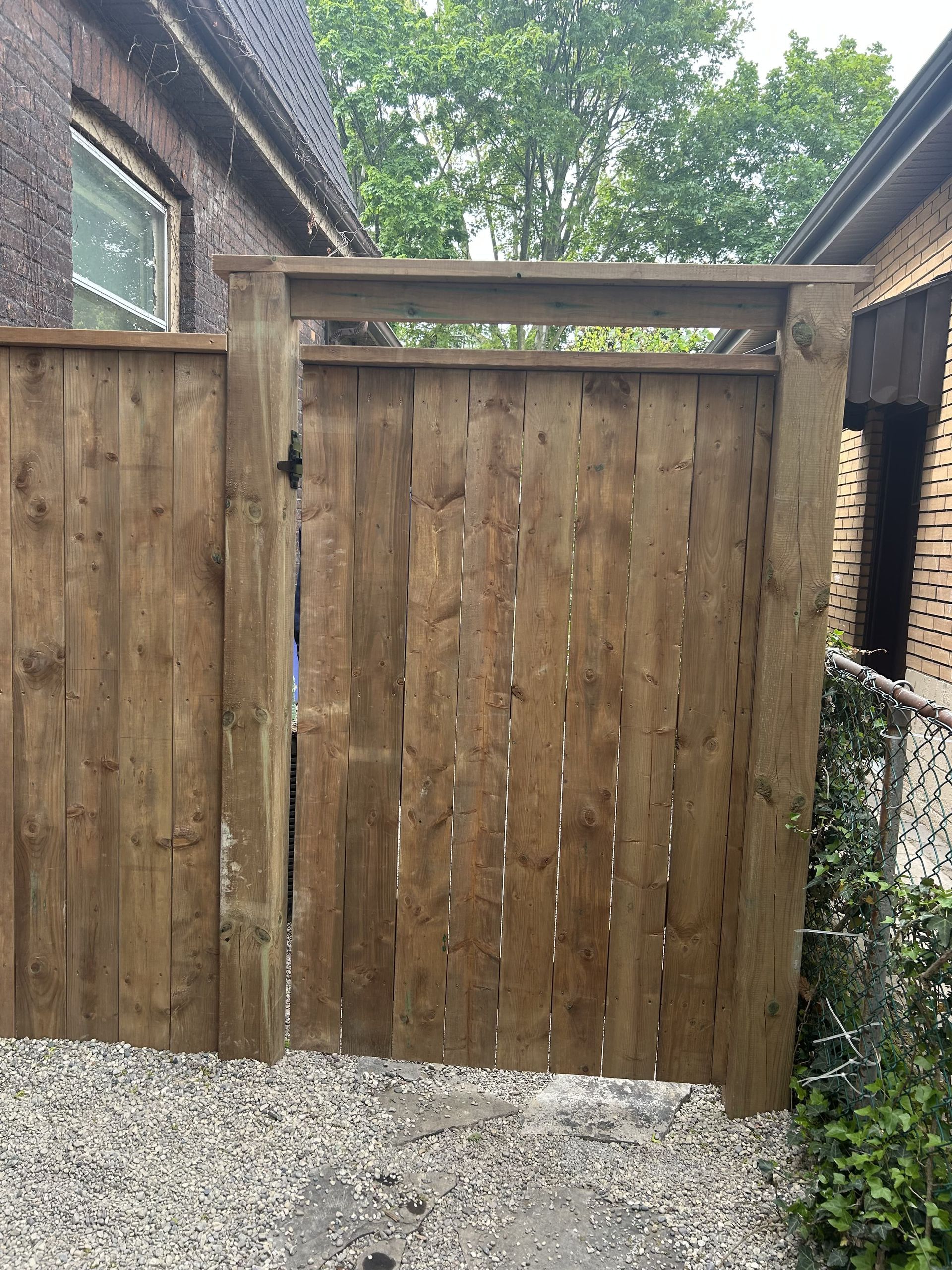 A wooden fence with a gate in front of a house.