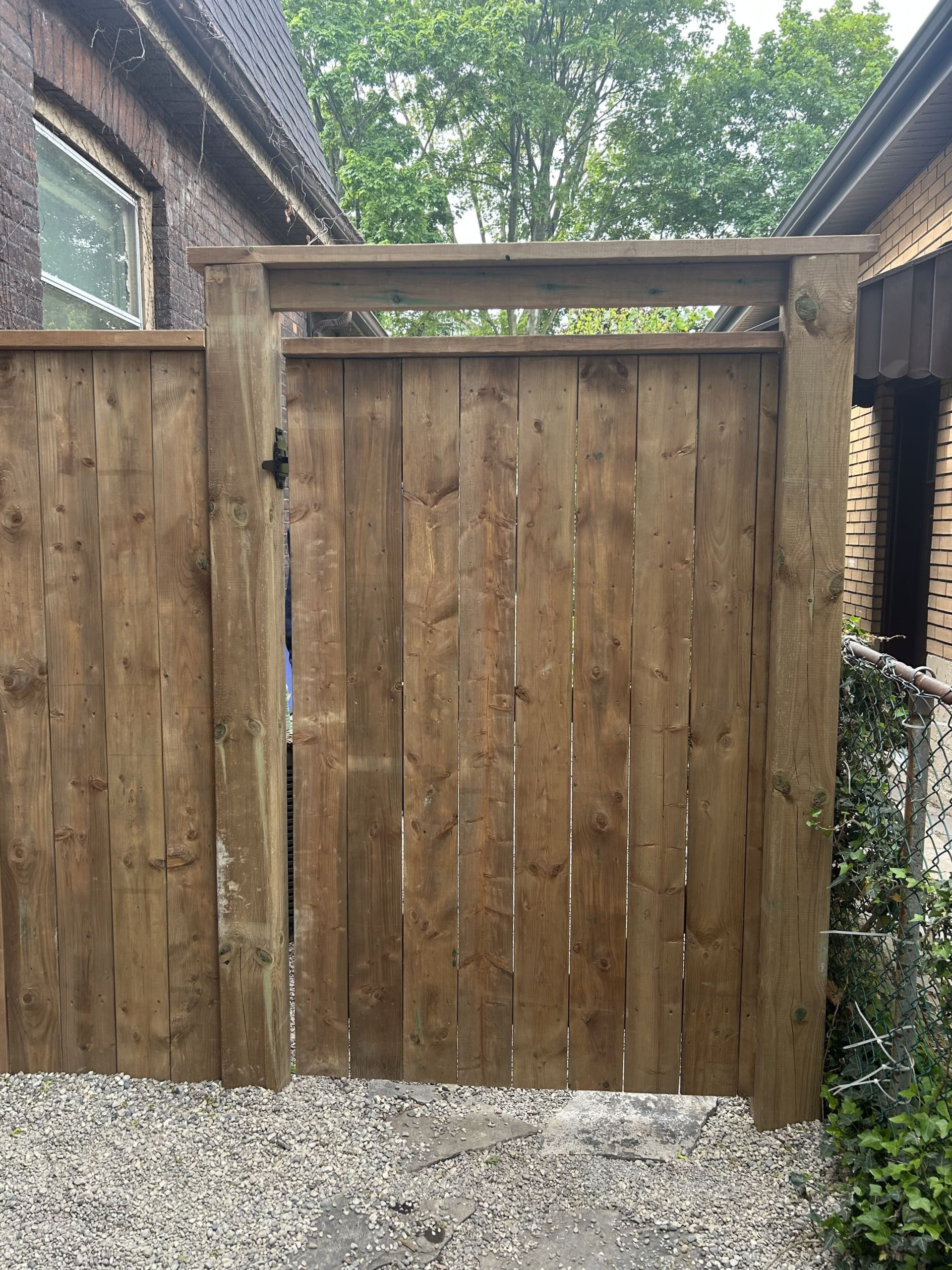A wooden fence with a gate in front of a house.