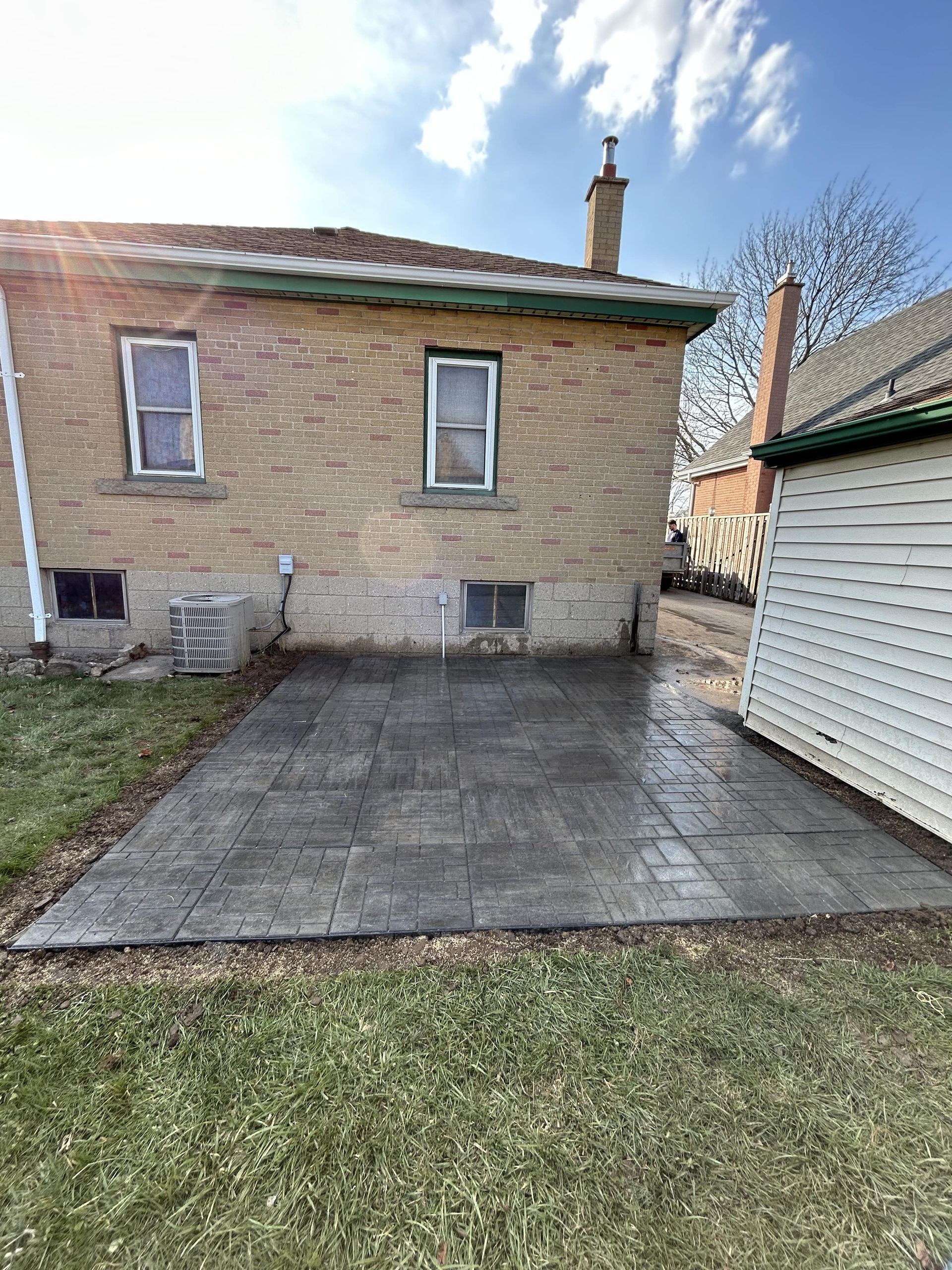 A brick house with a concrete driveway in front of it.