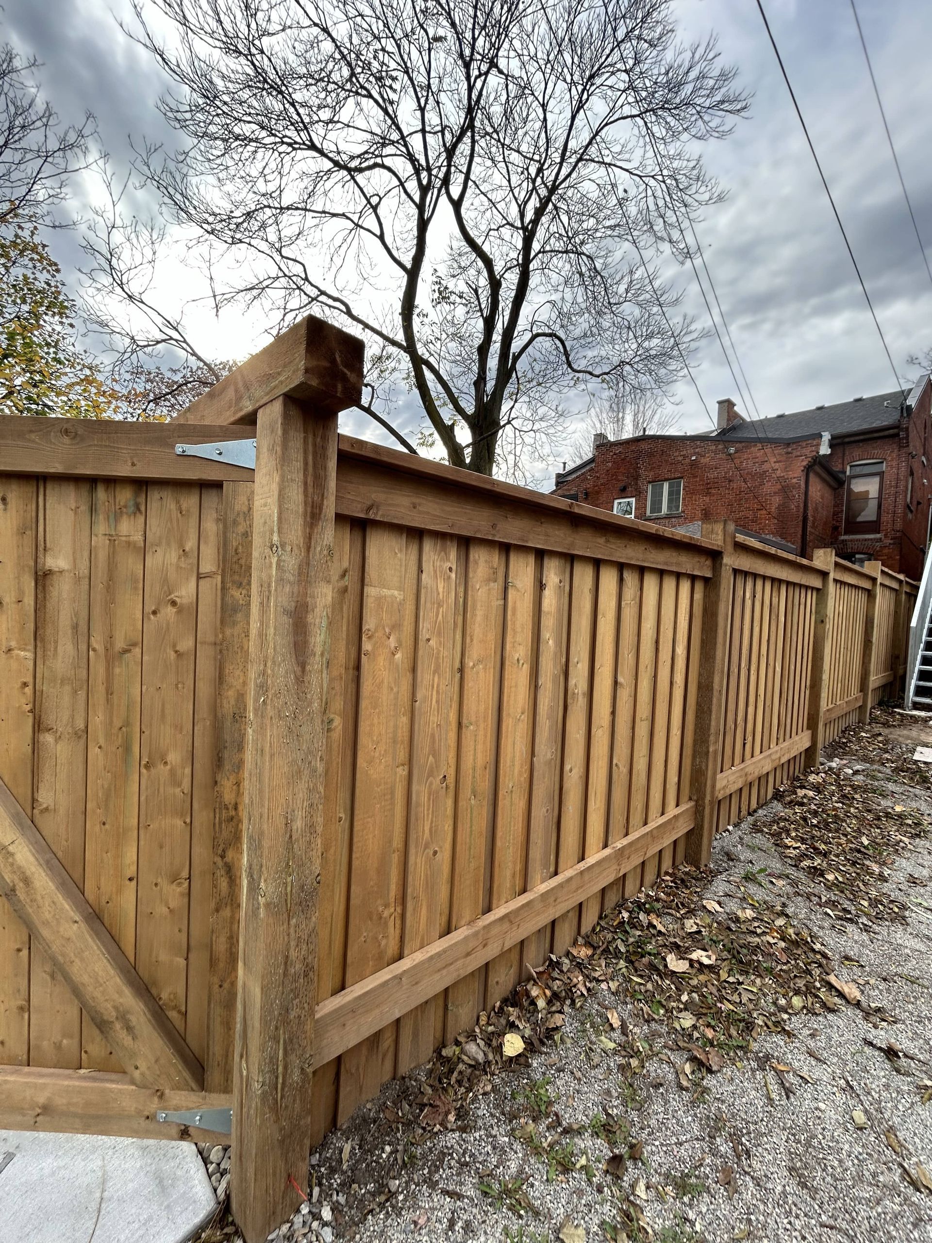 A wooden fence with a gate in the backyard of a house.