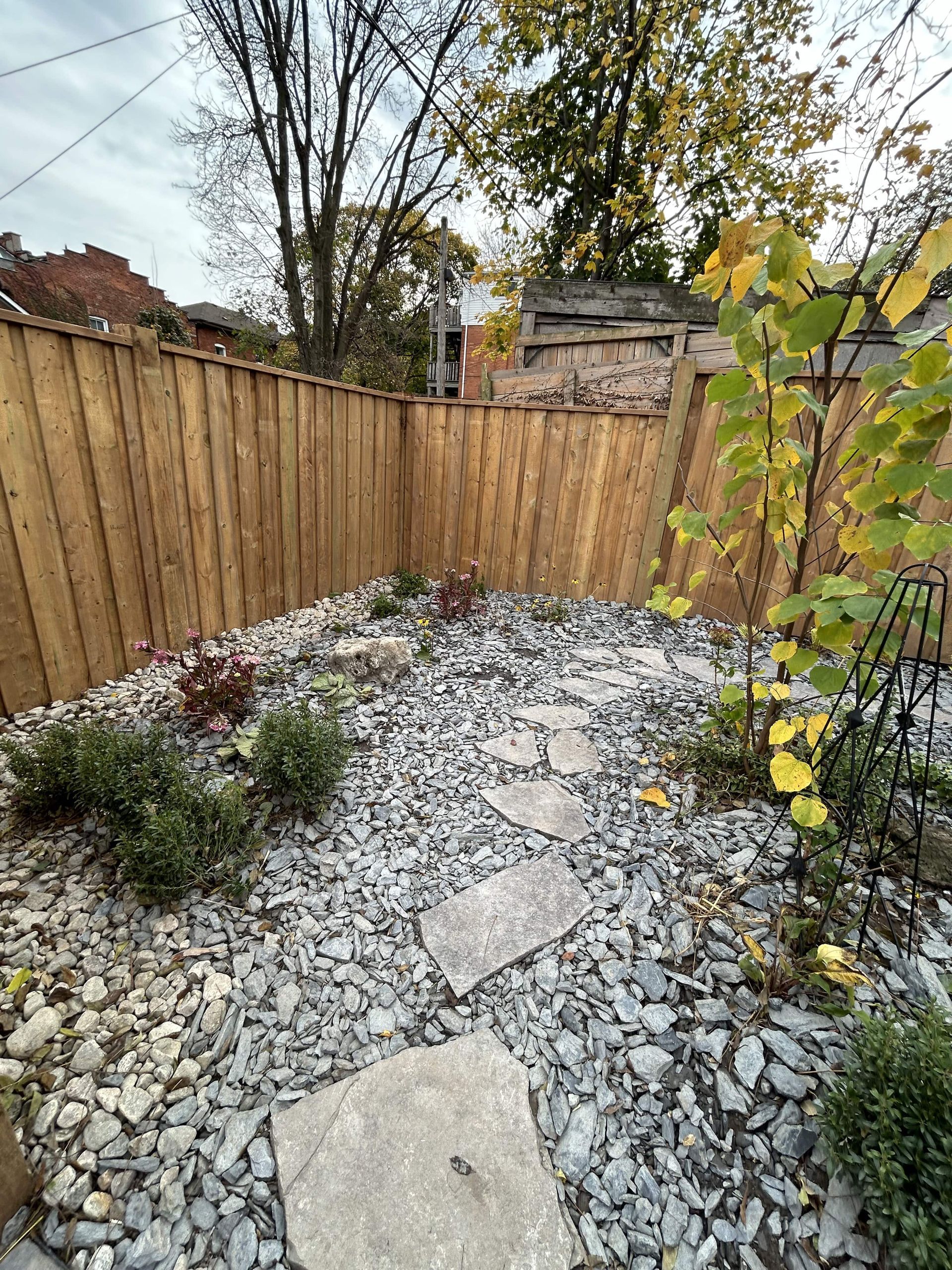 A backyard with a wooden fence and rocks.