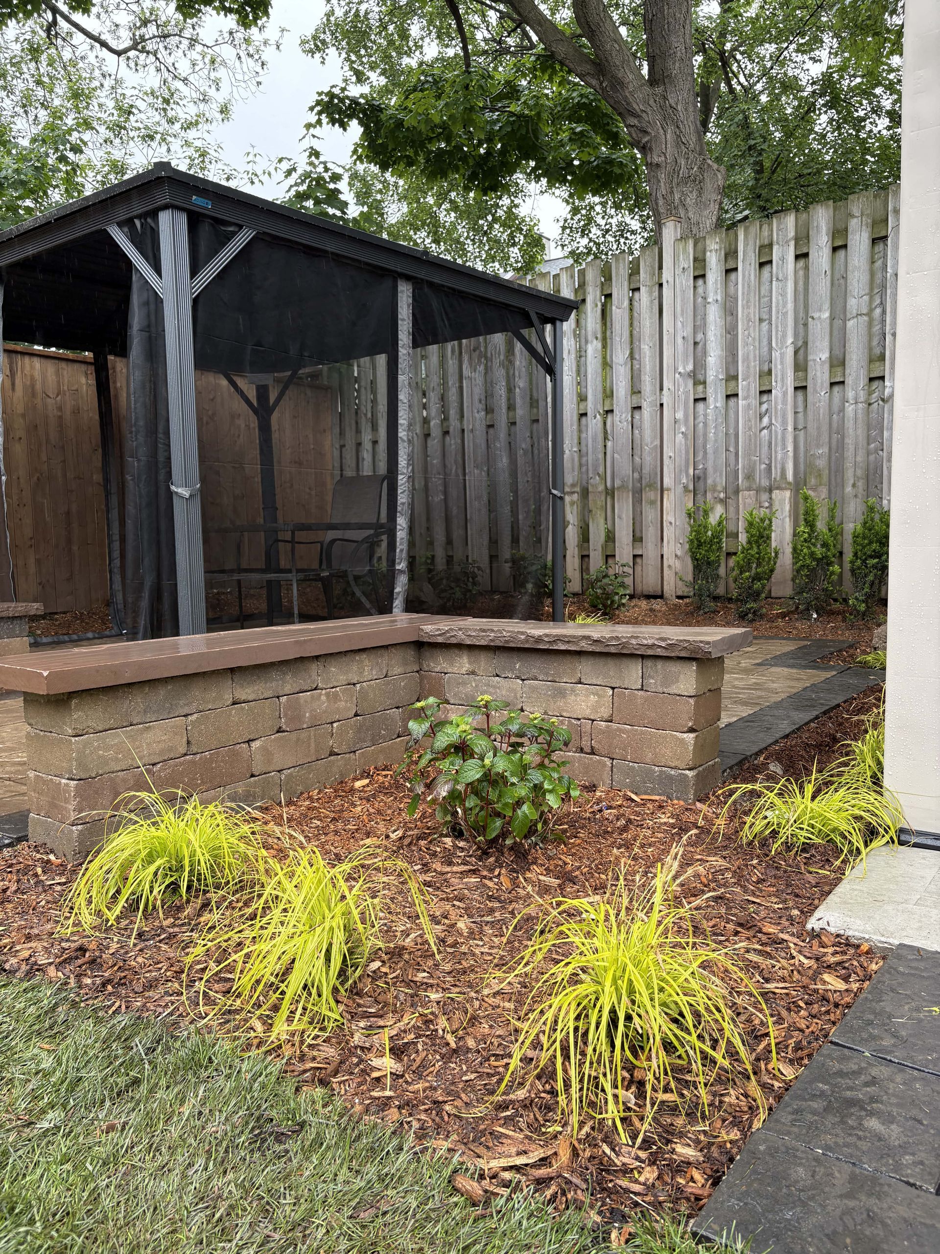 There is a gazebo in the backyard with a fence in the background.