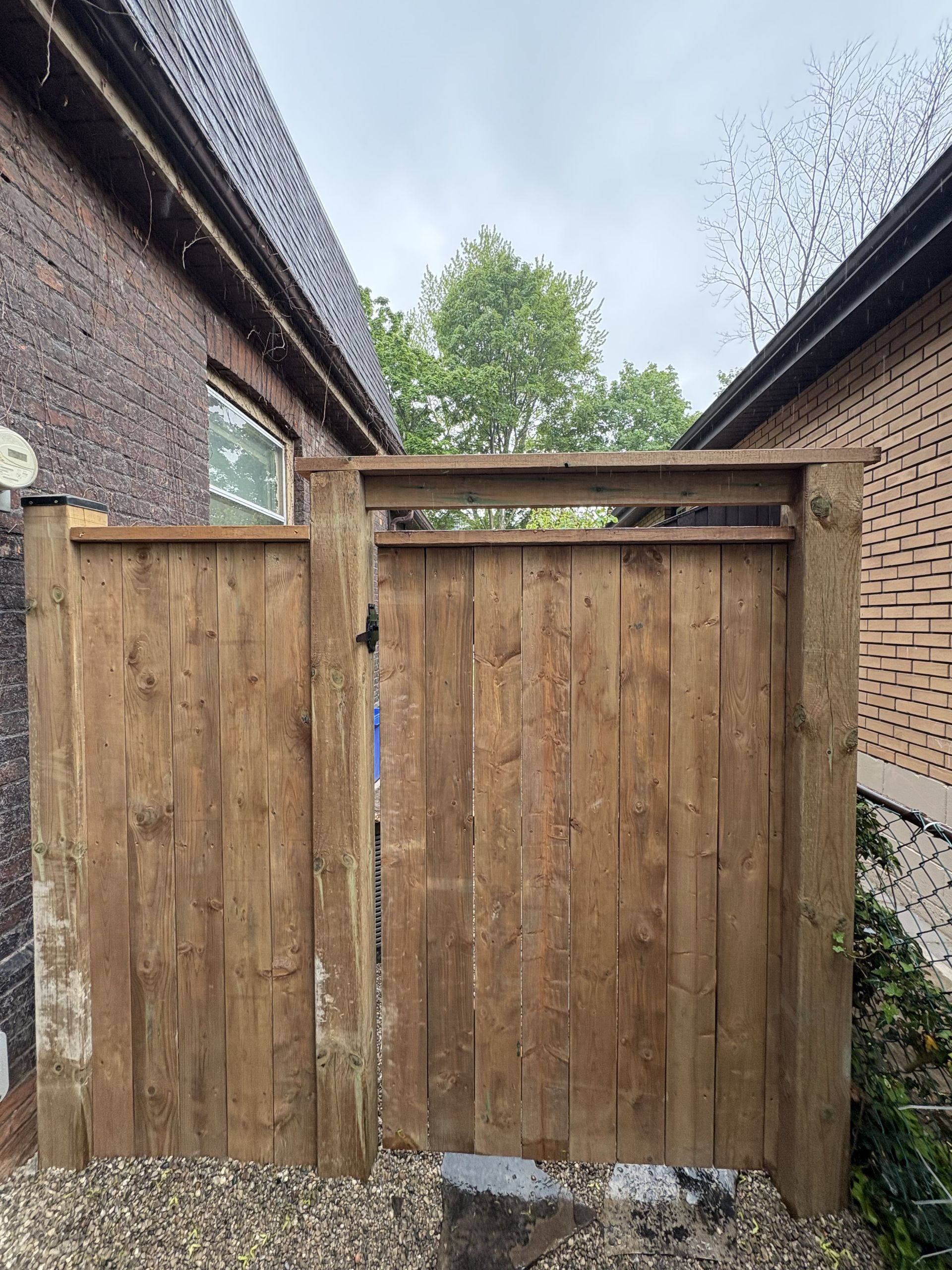 A wooden fence is sitting next to a brick building.