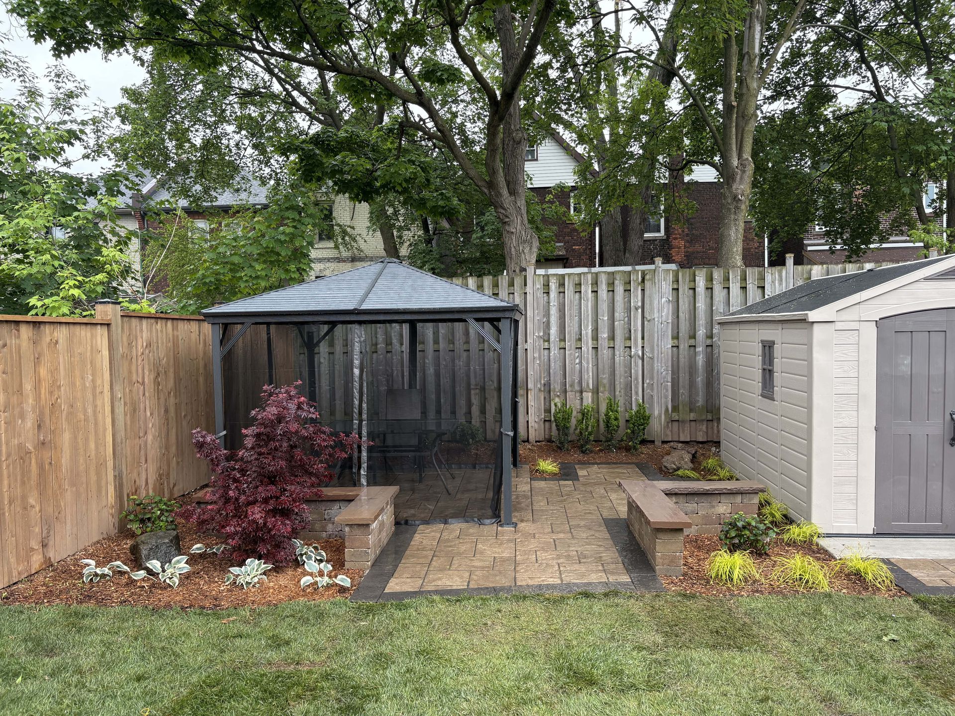 There is a gazebo in the backyard next to a shed.