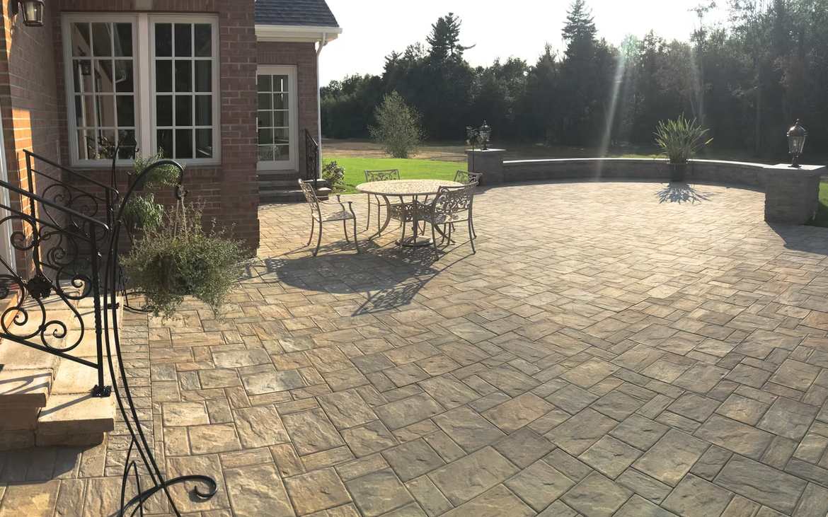A brick patio with a table and chairs in front of a brick house.