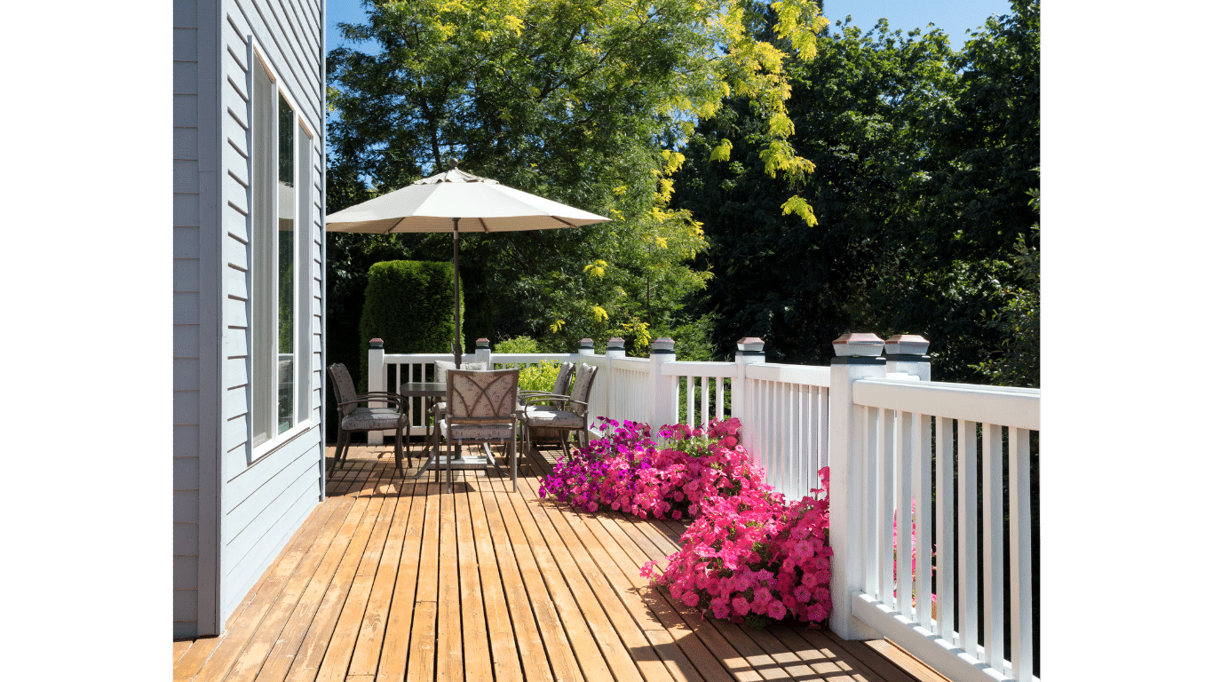 A wooden deck with a white railing and a table and chairs on it.