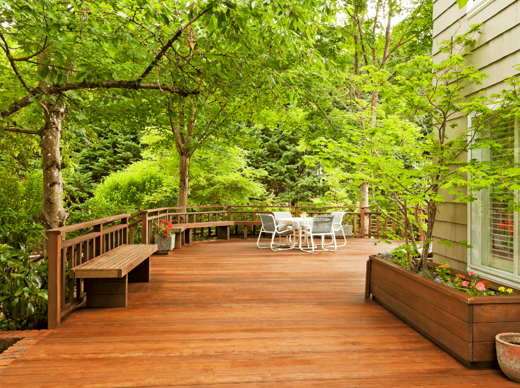 There is a wooden deck with a bench and a table and chairs on it.
