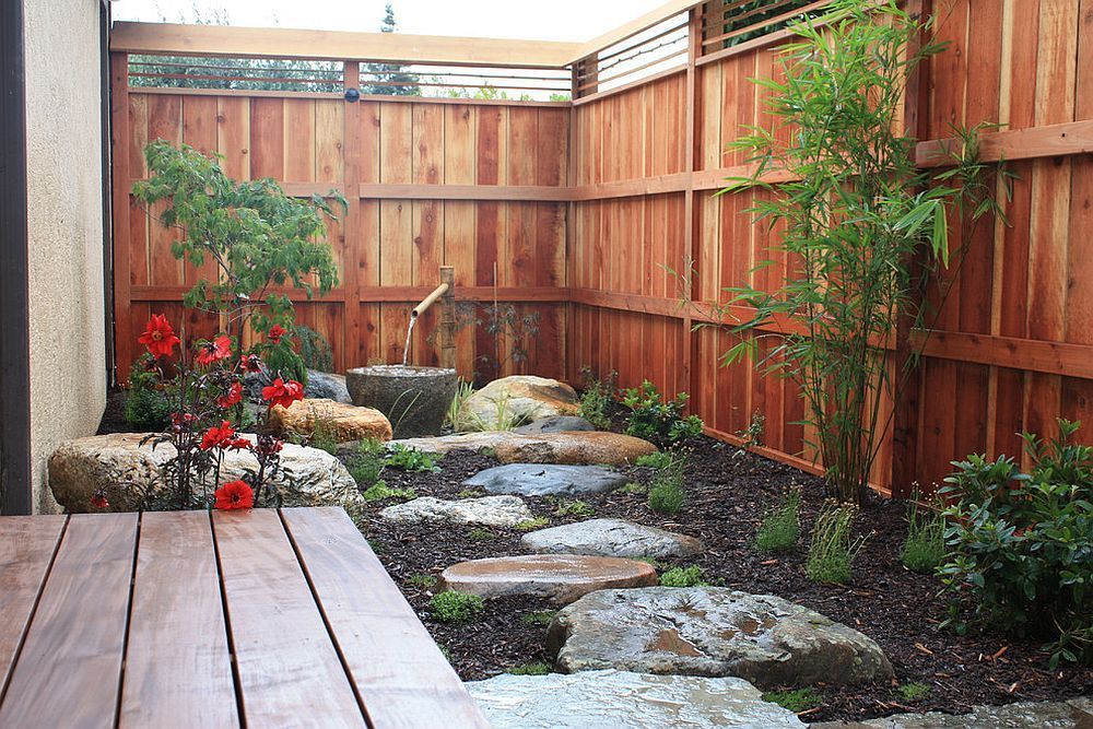 A wooden fence surrounds a garden with rocks and plants