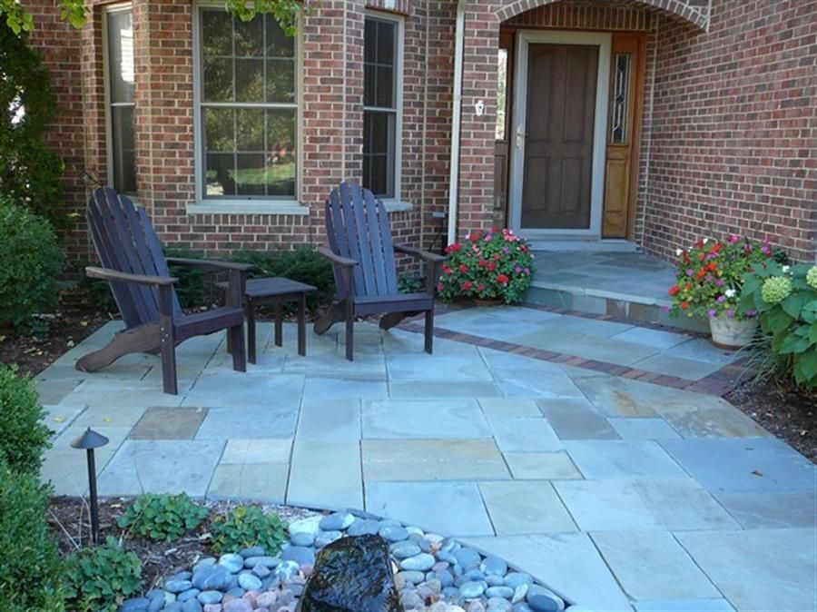 Two chairs are sitting on a patio in front of a brick house.