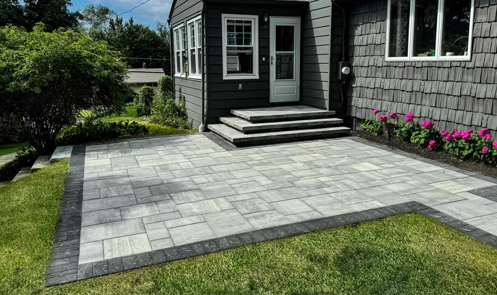 A black house with a patio in front of it.