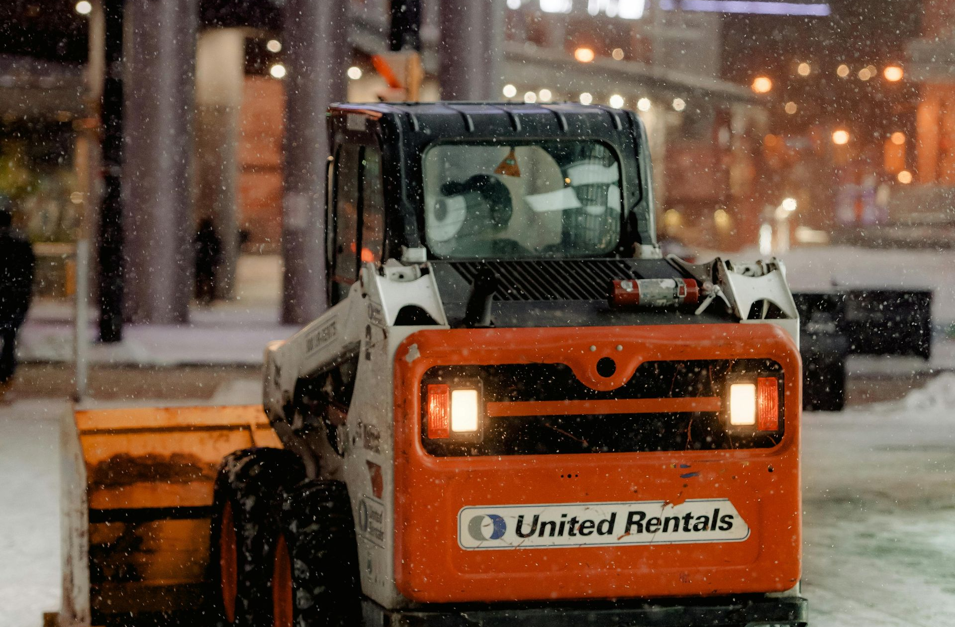 A snow plow is plowing snow on a city street.