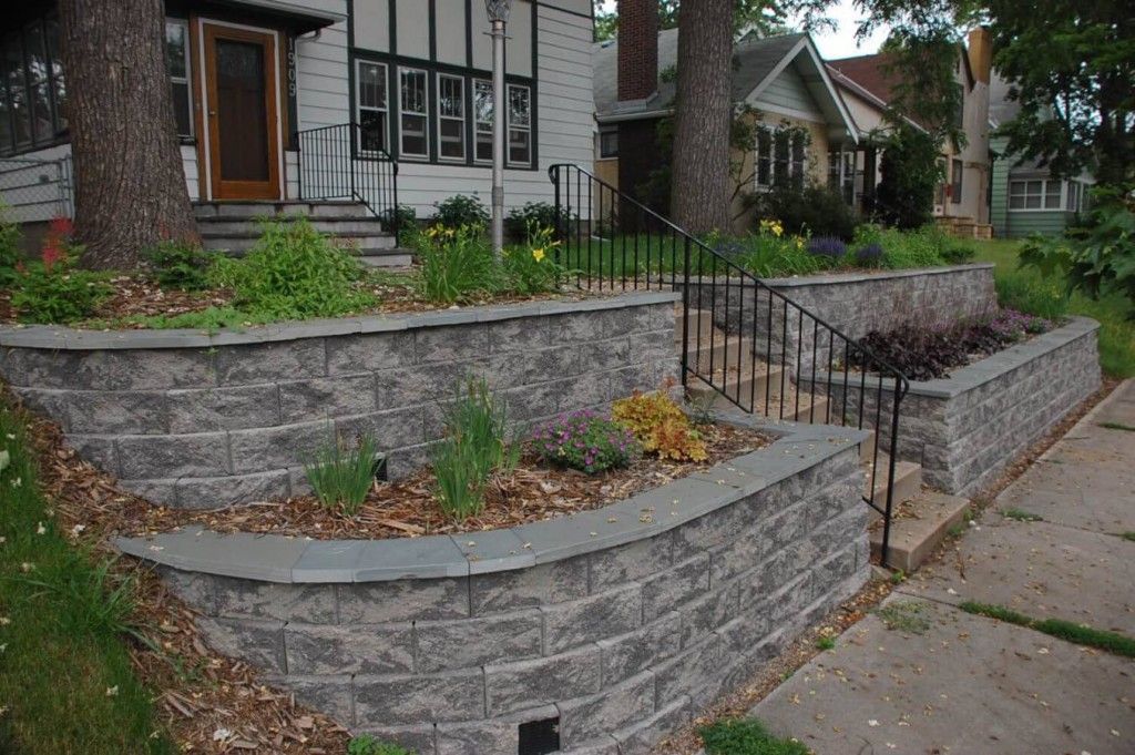 A house with a stone wall and stairs in front of it