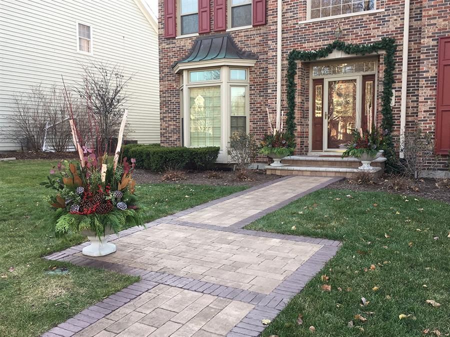 A brick walkway leading to the front door of a house decorated for christmas.