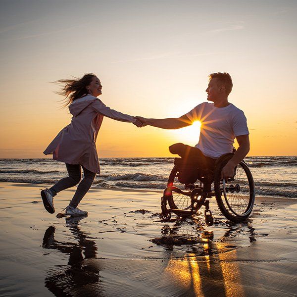 a woman holding the hands of a man in a wheelchair