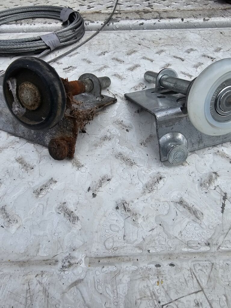 Side-by-side comparison of a new nylon garage door roller and rusted seized up roller that needed replacing