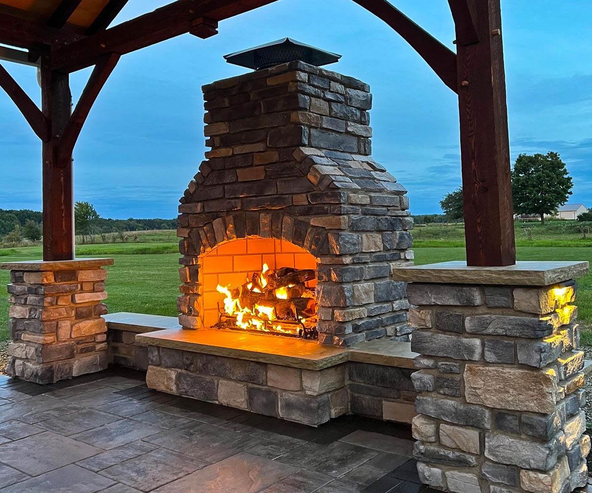 Roaring outdoor fireplace at dusk at Medina Ohio home installed by Medina landscape contractor Chidsey Landscape and Design