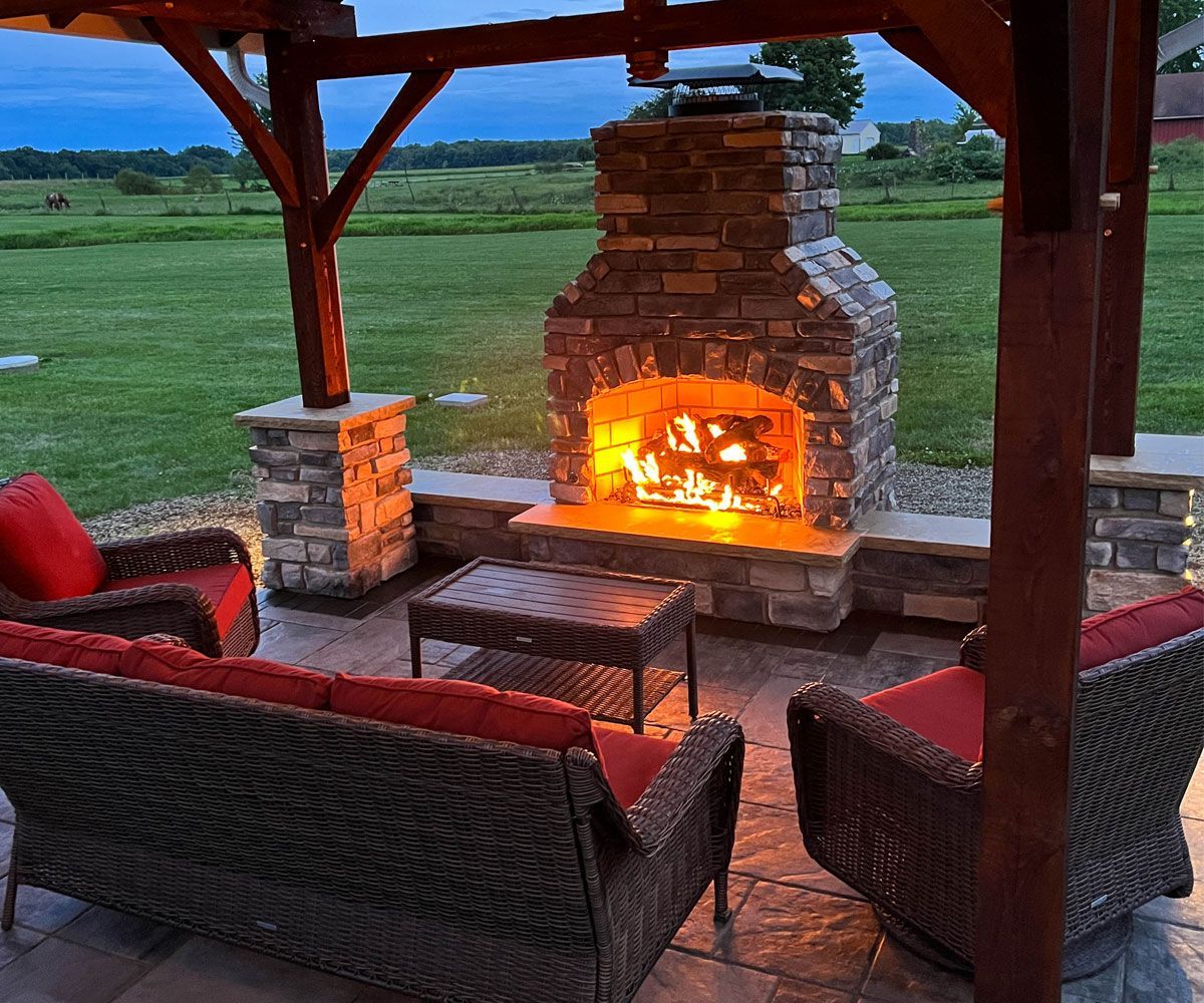 Custom outdoor stone fireplace under Bath, OH pavilion on Unilock paver patio.