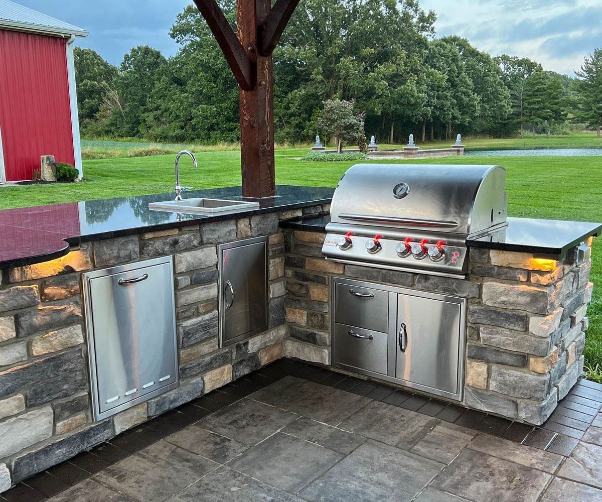 Custom Bath, Ohio outdoor kitchen on paver patio with built-in gas grill, outdoor refrigerator, prep area, and outdoor kitchen sink.